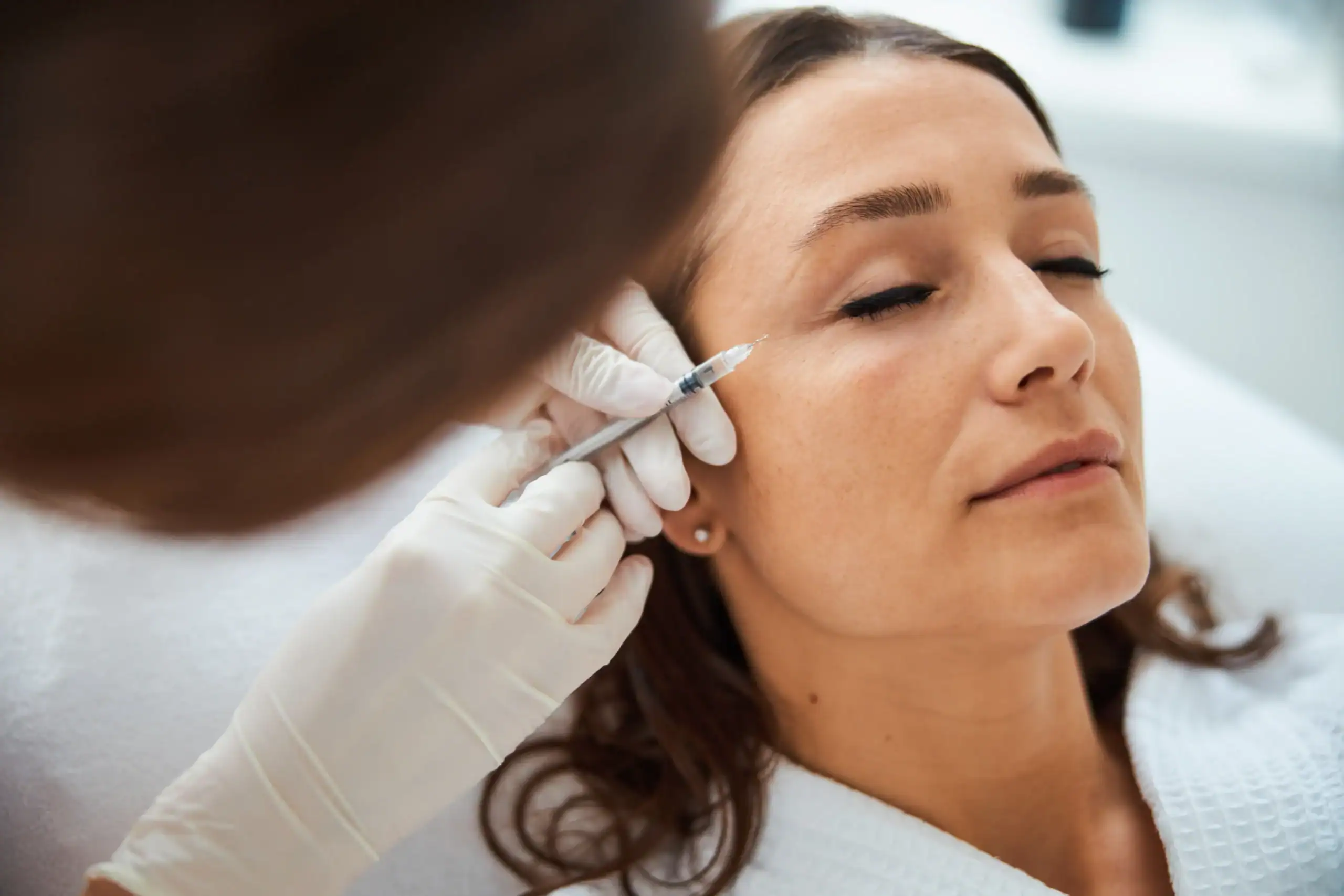 Woman gets a Botox shot to get rid of crow's feet around her eyes