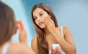 Young woman applying moisturizer