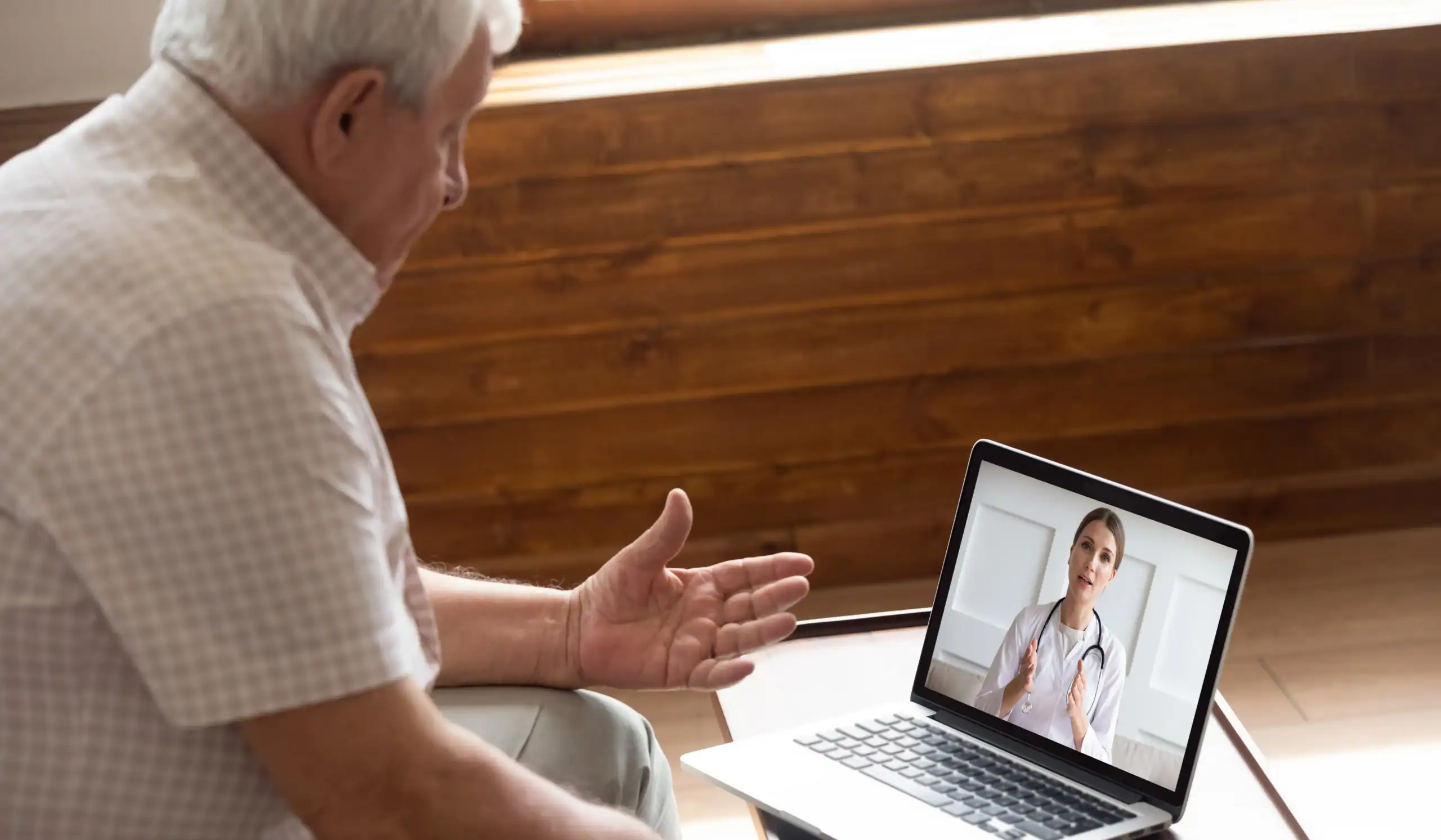 Older man talks to a dermatologist during a teledermatology visit via video