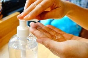 A person using a hand sanitizer pump dispenser.