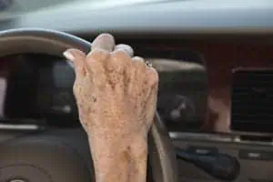 Woman’s hand on steering wheel with age spots