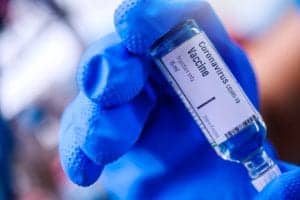 Gloved hand holding coronavirus vaccine.