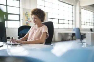 Woman at work desk near large windows 