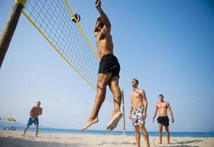 Young men playing beach volleyball.