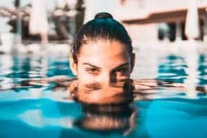 young woman swimming after applying sunscreen