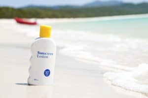 Closeup of sunscreen bottle next to the ocean