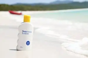 Closeup of sunscreen bottle next to the ocean