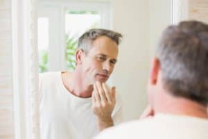 Man examining his face in mirror