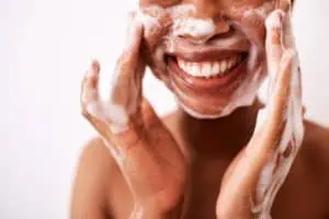 Woman washing her face with a foaming cleanser to prevent oily skin