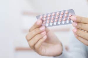 Woman holding birth control pills