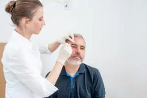 A nurse practitioner treating a male dermatology patient.