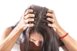 Woman with itchy scalp scratching her head