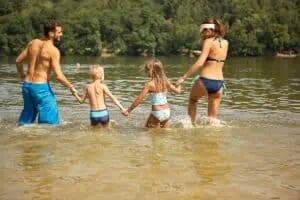 A family wades into a lake that may be contaminated with lake parasites that cause swimmer’s itch