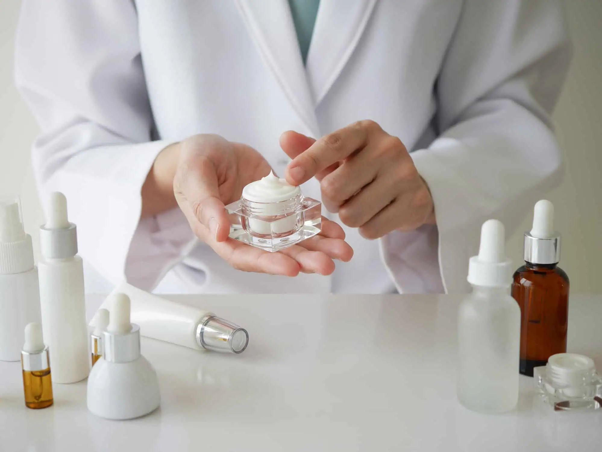 Woman in lab coat holding skin care products
