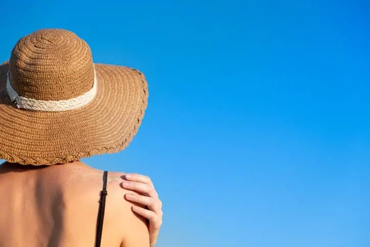 woman in sunhat and swimsuit gets sun