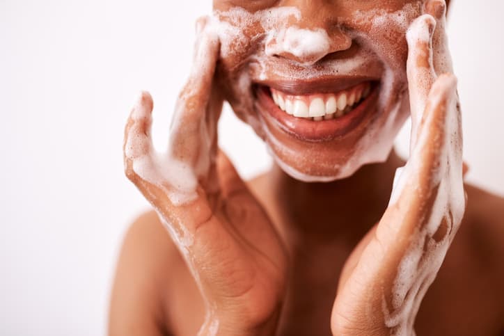 Woman rubbing soapy lather on her face.
