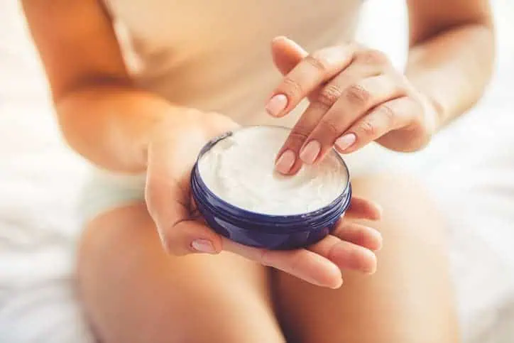Woman with her finger in a jar of lotion