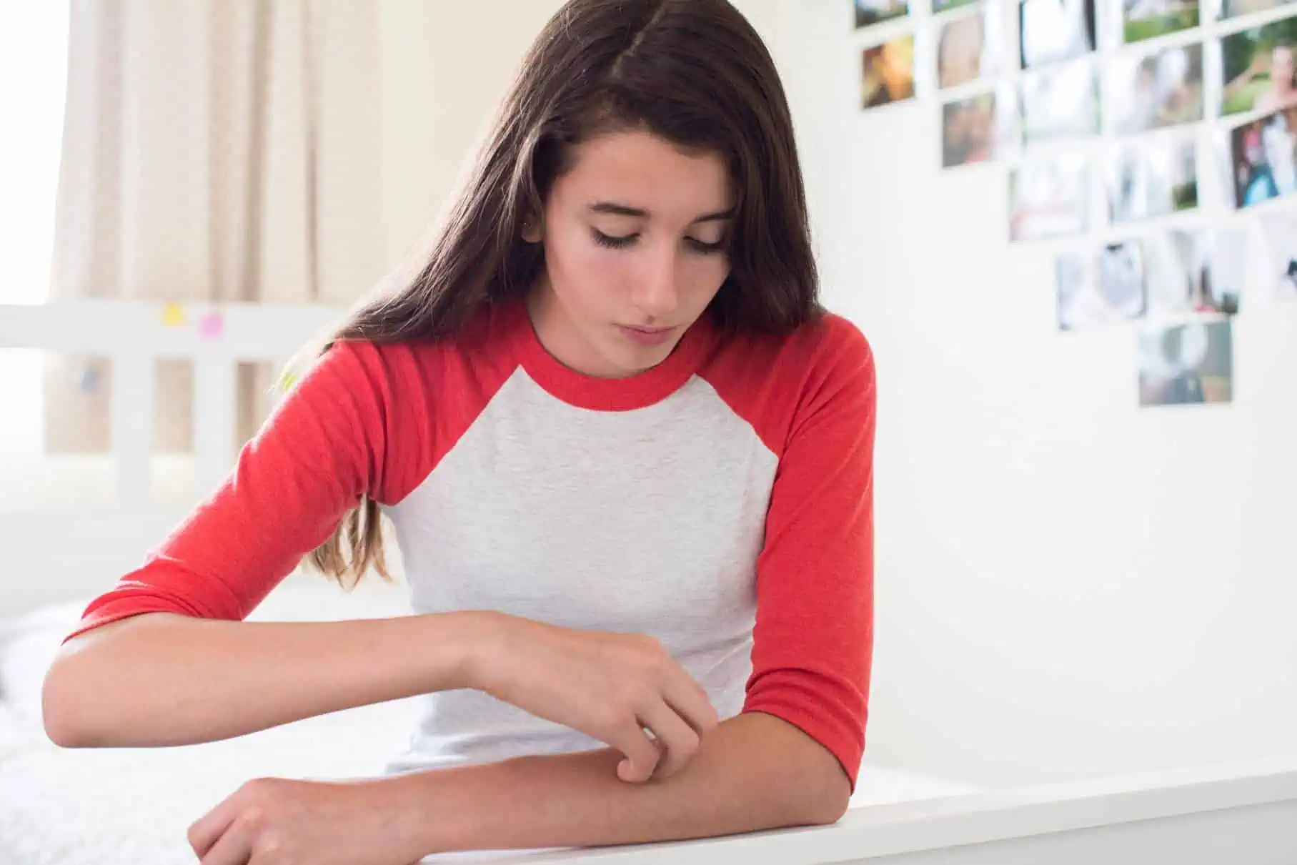 Teenage girl examining the skin of her arm