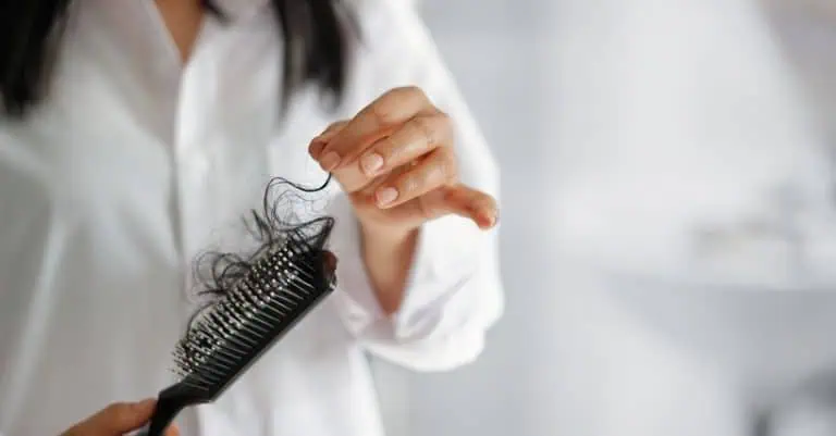 Woman pulling hair out of her brush.