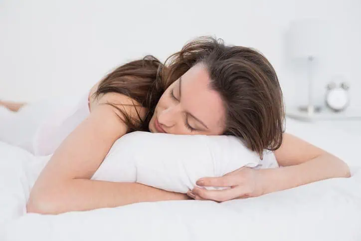 Woman asleep with her head on a pillow.