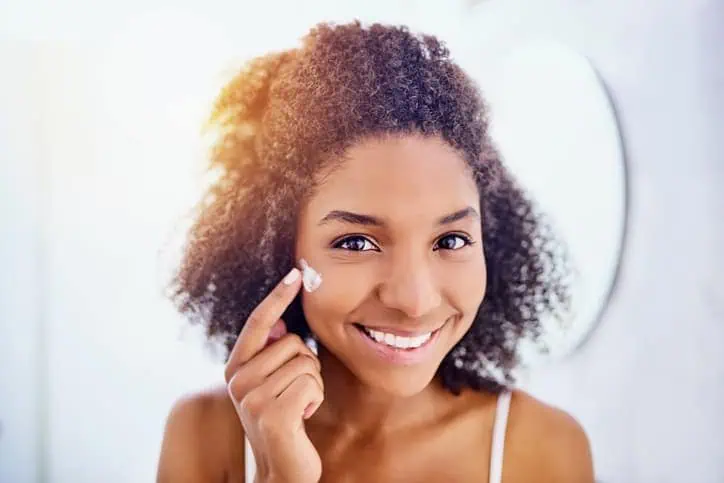 Woman applying face cream to her cheek