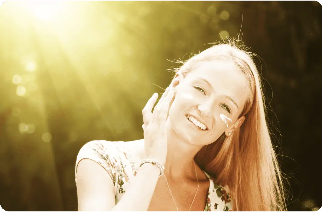 Woman applying sunscreen to her face.