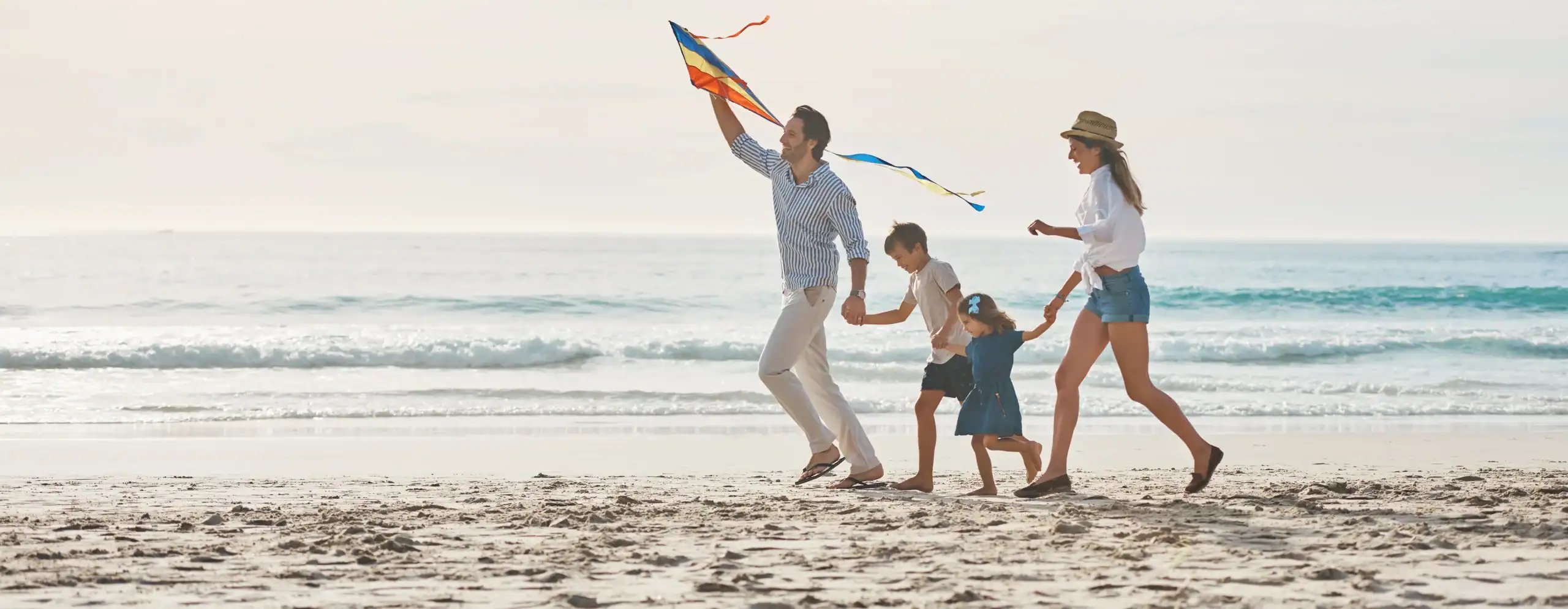 Family runs with kite on beach