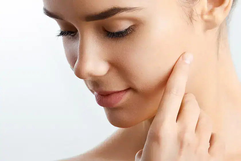 Young woman with great skin touches her face