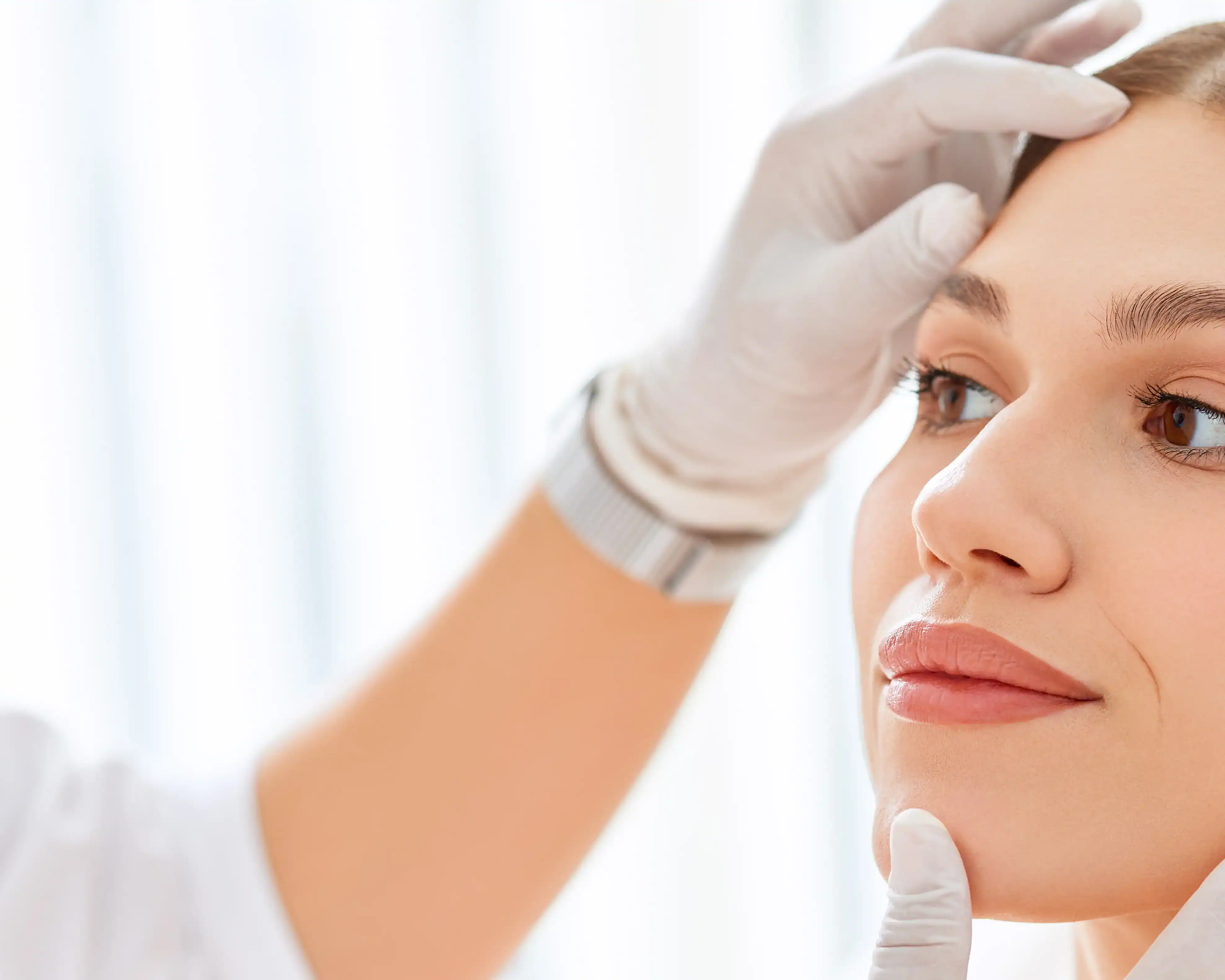 Aesthetician examines a young woman's face before a treatment