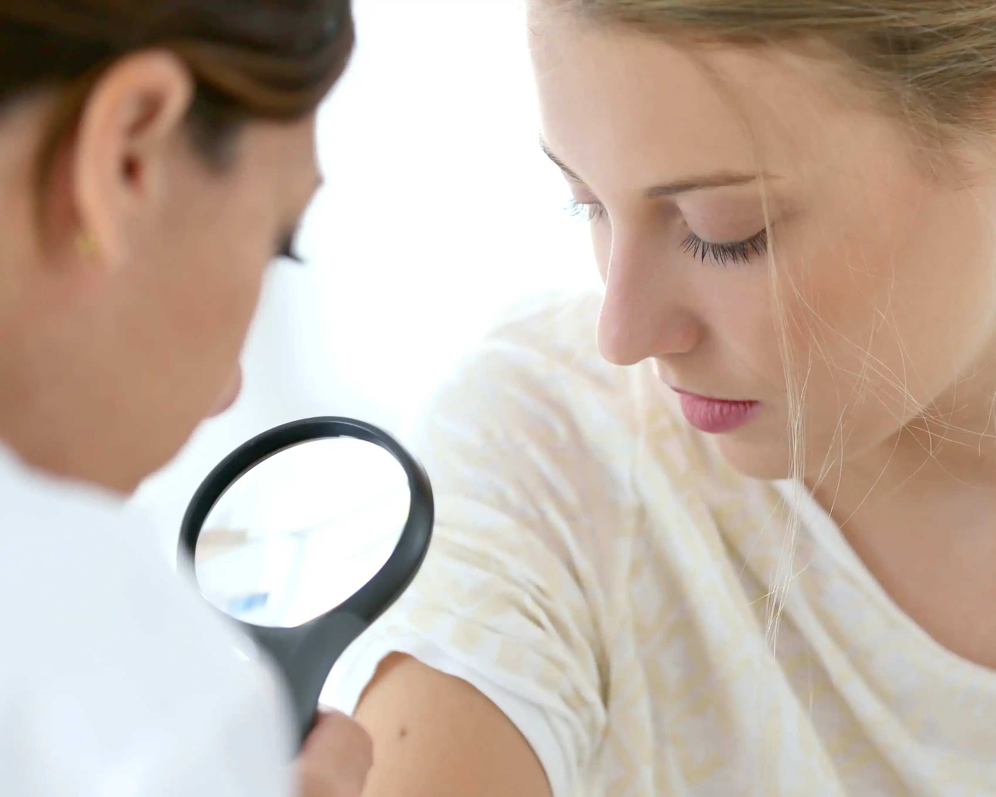 Woman gets a spot on her arm checked during a medical dermatology appointment