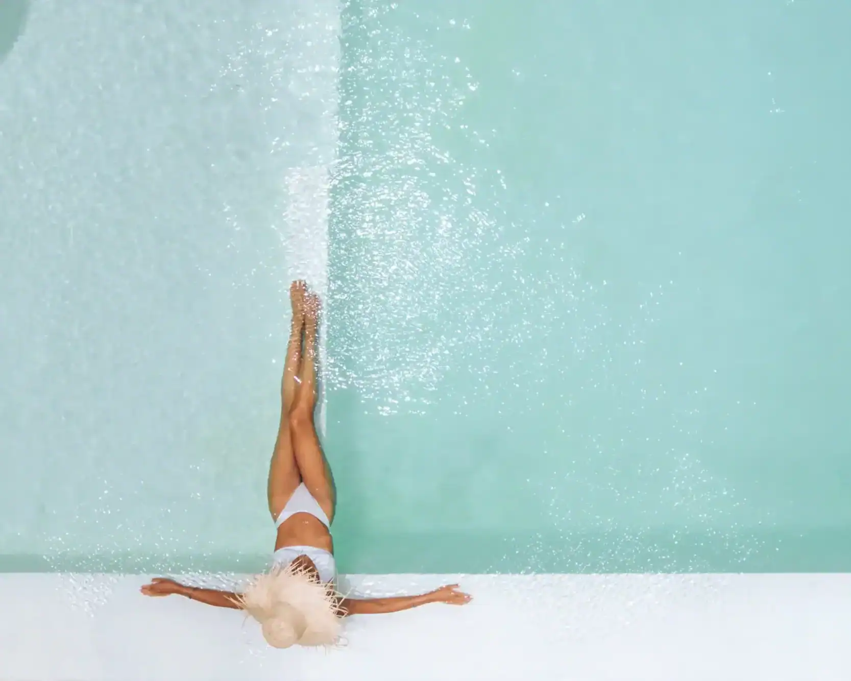 Beautiful woman with hat in the turquoise water of a pool