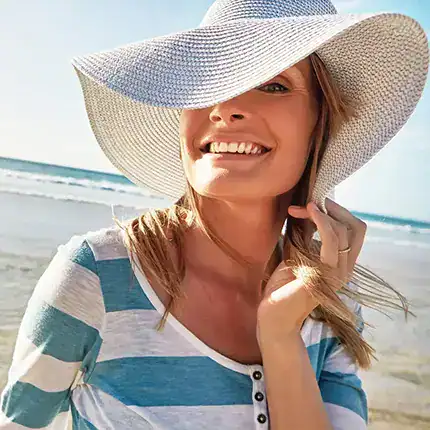 Woman in a sun hat and teal-striped shirt enjoys the sun
